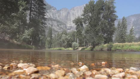 Throwing-Multiple-Stones-In-The-Merced-River-With-The-Columbia-Rock-In-The-Background,-Yosemite-National-Park