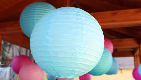 a large blue paper lantern hanging under a wooden structure