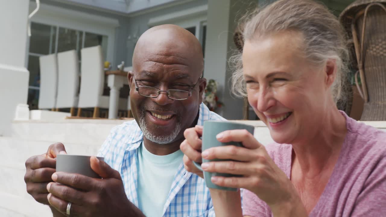feliz pareja de alto nivel con camisas y bebiendo café en el jardín