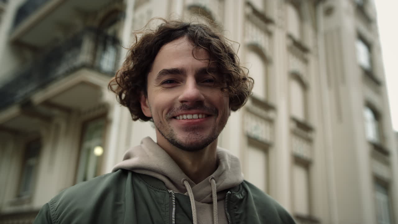 Uomo allegro che sorride in strada. Hipster gioioso felice nel centro storico.
