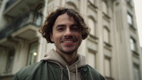 hombre alegre sonriendo en la calle urbana. hipster alegre sintiéndose feliz en el casco antiguo.