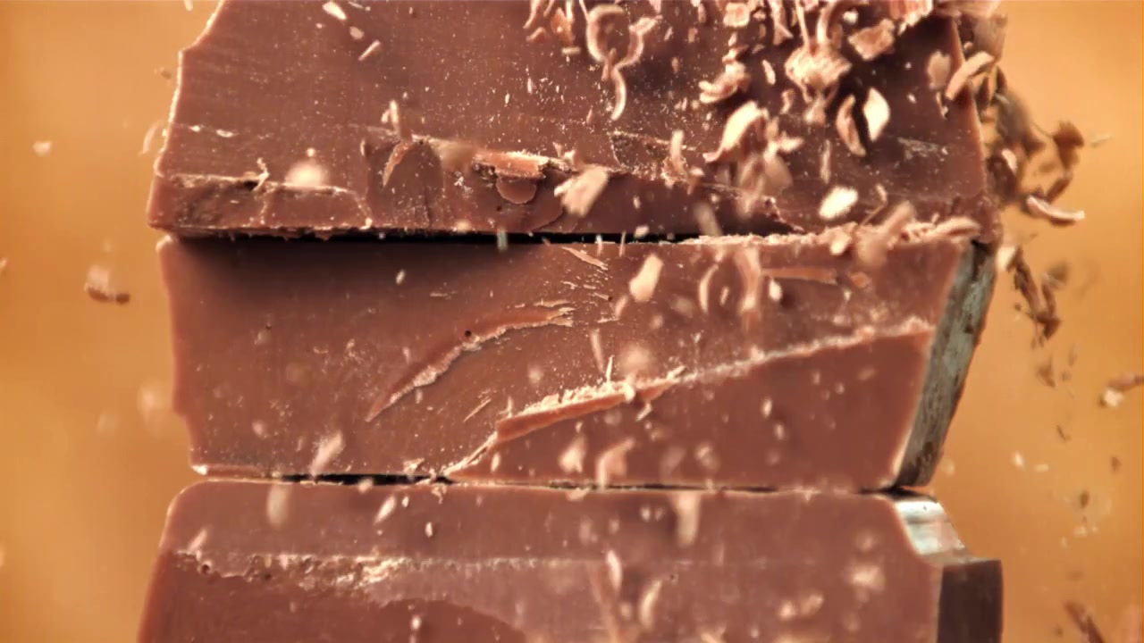 Movimento rallentato di scaglie di cioccolato che cadono su barrette di cioccolato impilate