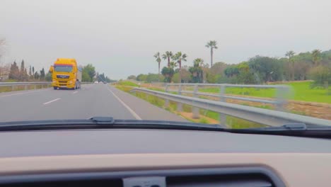 a fast drive view from the windscreen of a car making amaze of travel on the highway of mallorca, spain, with lush greenery in rainy weather, light and heavy traffic passing from the other side
