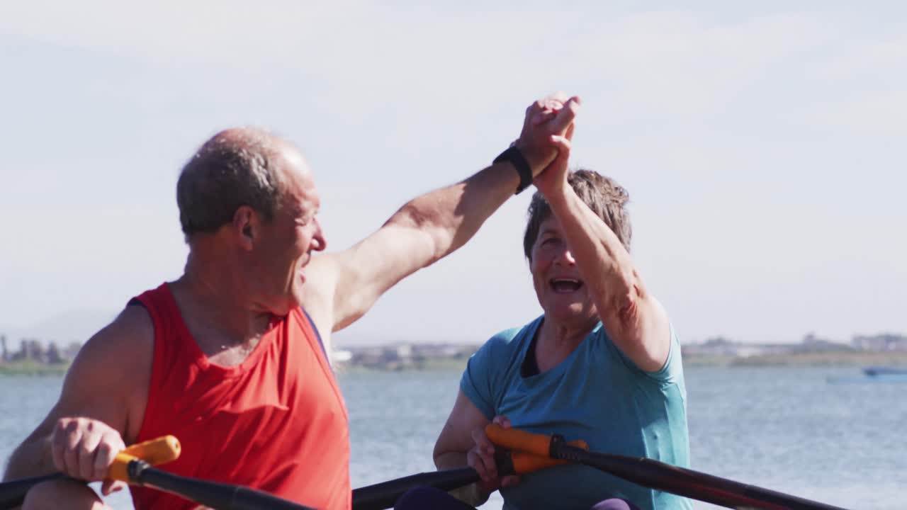 Senior caucasian man and woman in rowing boat high fiving