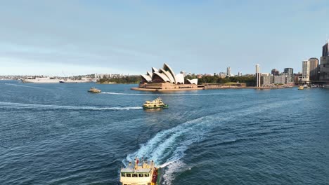 impresionante toma de aproximación aérea del monumento australiano de la ópera de sídney con los transbordadores de pasajeros debajo, australia