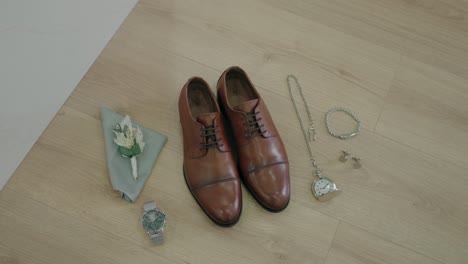 brown leather shoes with silver jewelry watch boutonniere and pocket watch on wood floor