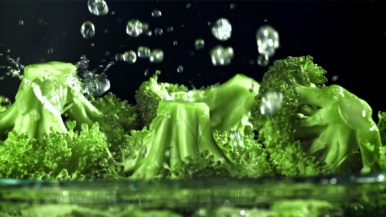 Schizzi d'acqua al rallentatore su broccoli freschi e verdi