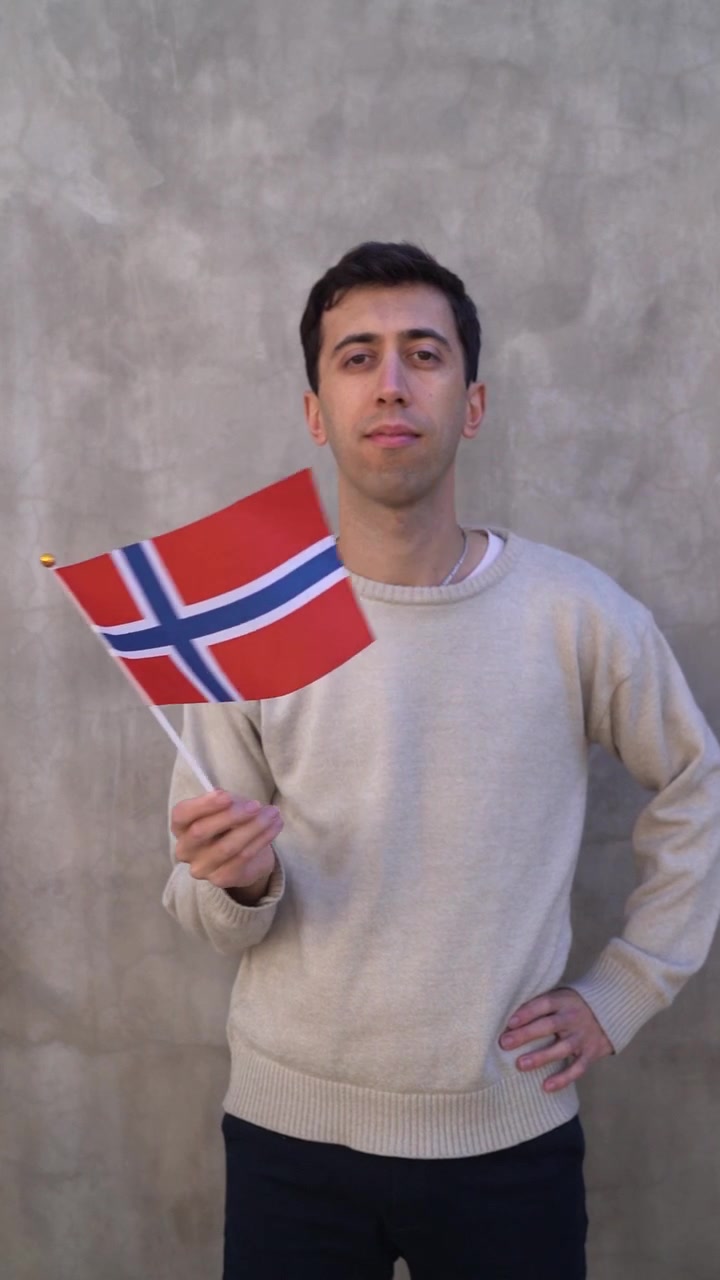 Dorosły mężczyzna machający flagą Norwegii. Zwolnione tempo. Ujęcie pionowe.