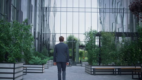 confident businessman walking downtown area rear view. modern office building.