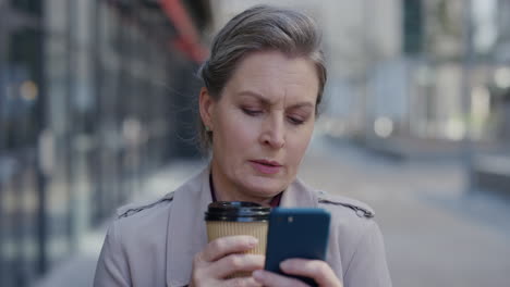 Retrato-De-Una-Exitosa-Mujer-De-Negocios-Senior-Usando-Un-Teléfono-Inteligente-En-La-Ciudad-Tomando-Café-Navegando-Mensajes-Enviando-Mensajes-De-Texto-En-Un-Teléfono-Móvil-Estilo-De-Vida-Urbano-Profesional-En-Cámara-Lenta