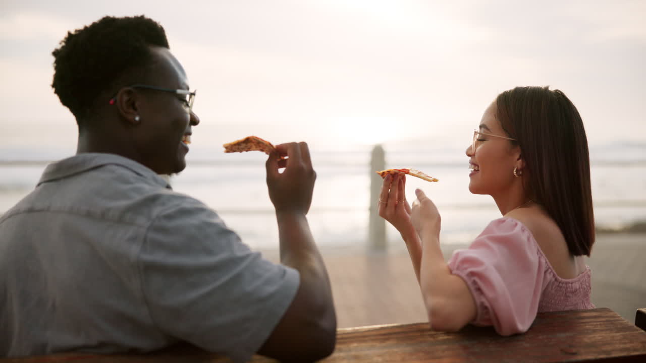 Coppia che mangia pizza sulla spiaggia
