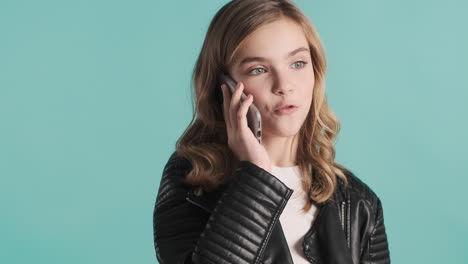 una adolescente caucásica con una chaqueta de cuero haciendo una llamada telefónica.