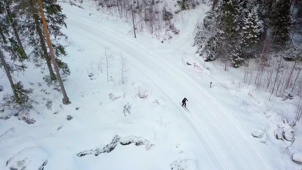Ripresa aerea che segue uno sciatore di fondo in una foresta innevata