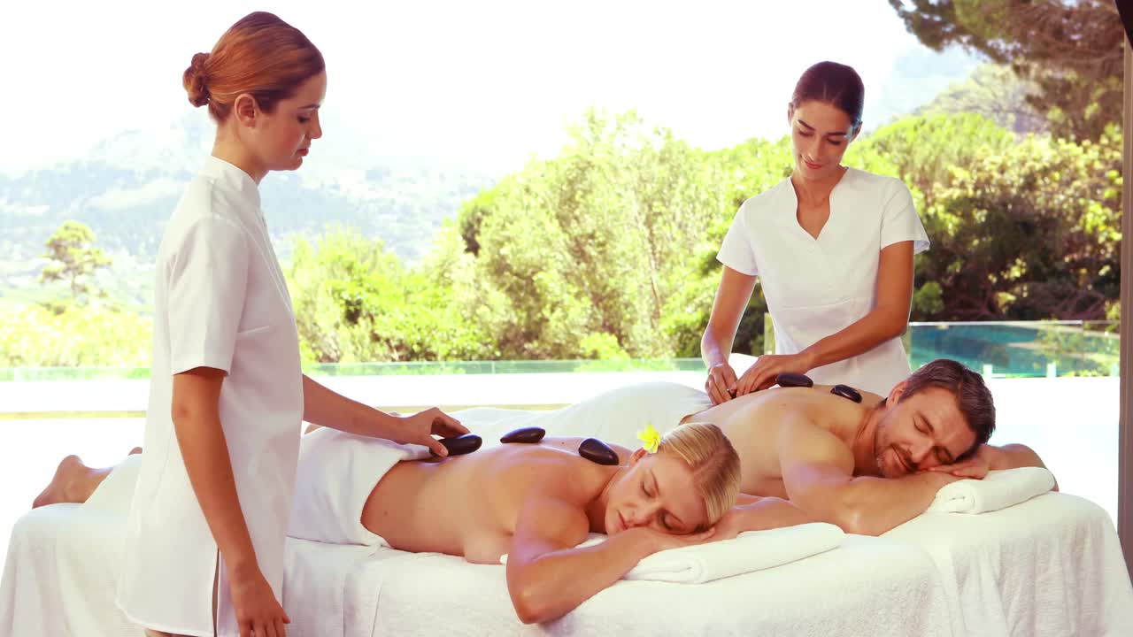 편안 한 부부 에게 뜨거운 돌 마사지 를 하는 즐거운 마사지사 들