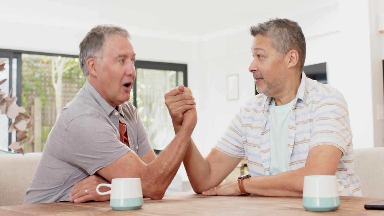 Dos amigos mayores haciendo pulso, disfrutando de tiempo juntos en casa con café.