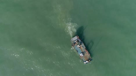 Top-down-aerial-of-a-Mussel-farming-open-sea-workboat-harvesting-in-a-calm-murky-green-ocean-sea