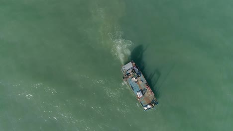 antena de arriba hacia abajo de un barco de trabajo de mar abierto para el cultivo de mejillones en un mar verde y turbio y tranquilo