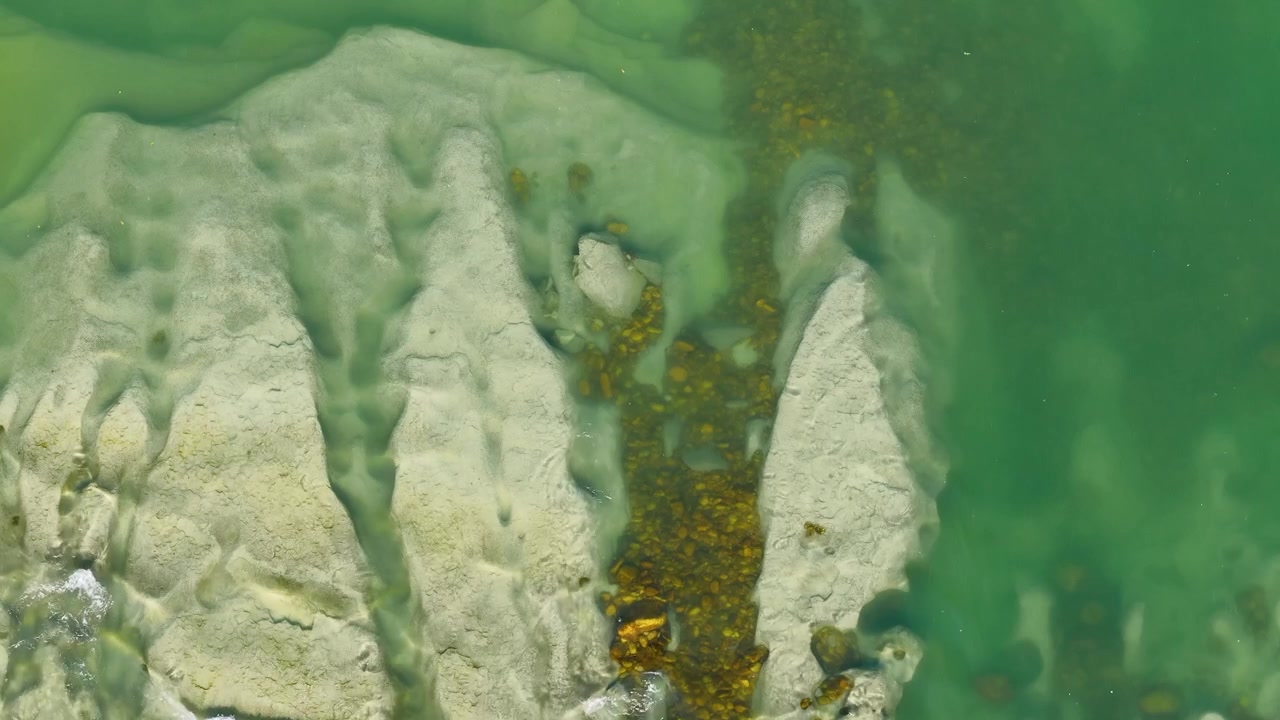 Ripresa aerea dall'alto di acqua limpida e turchese del fiume che scorre su rocce e sedimenti di colore chiaro