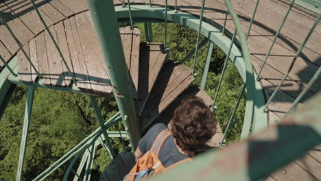 man walking up a spiral starway on top of a lookout tower on mountain boč