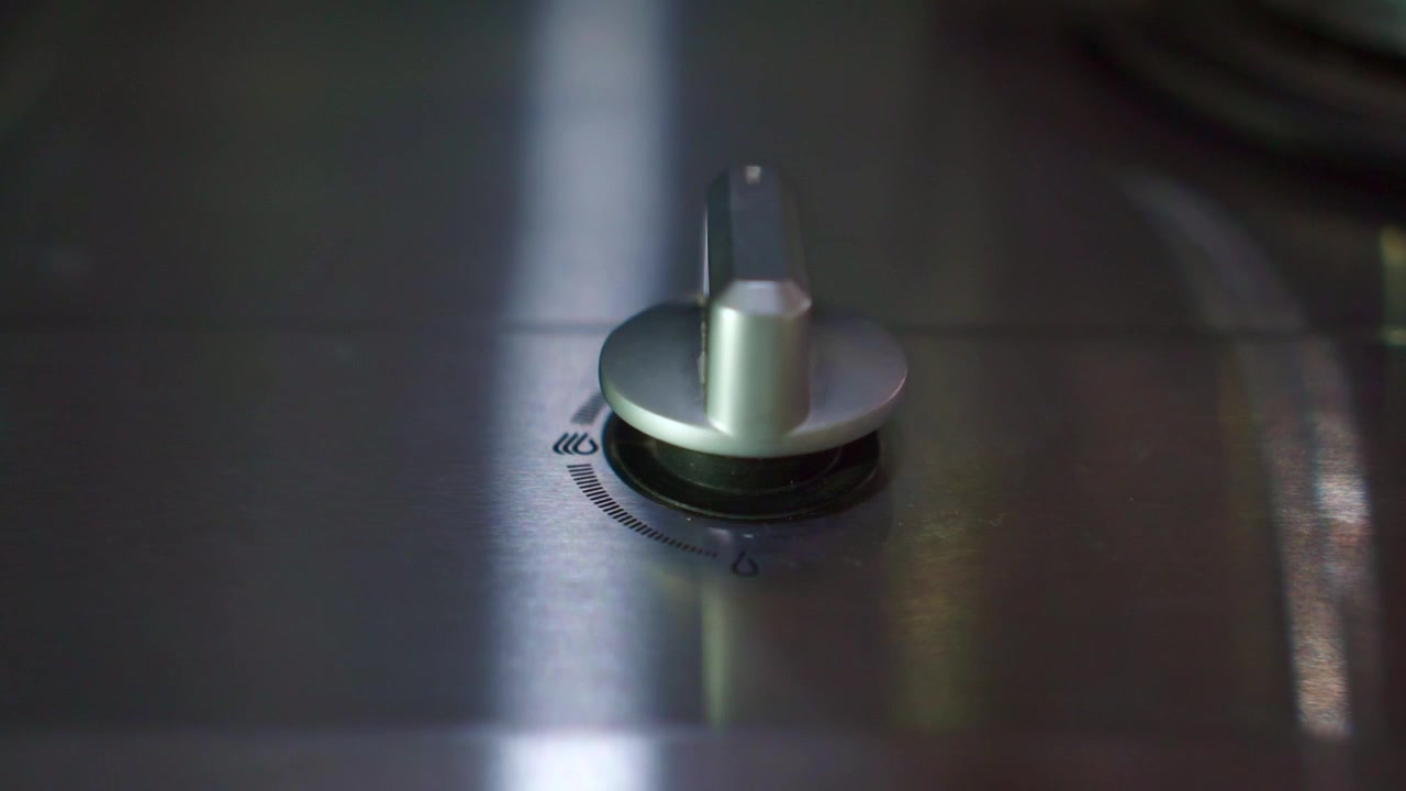 Fingers turning gas cooker knob, starting burner flame. Home kitchen appliance, cooking lifestyle concept, culinary stock footage clip.