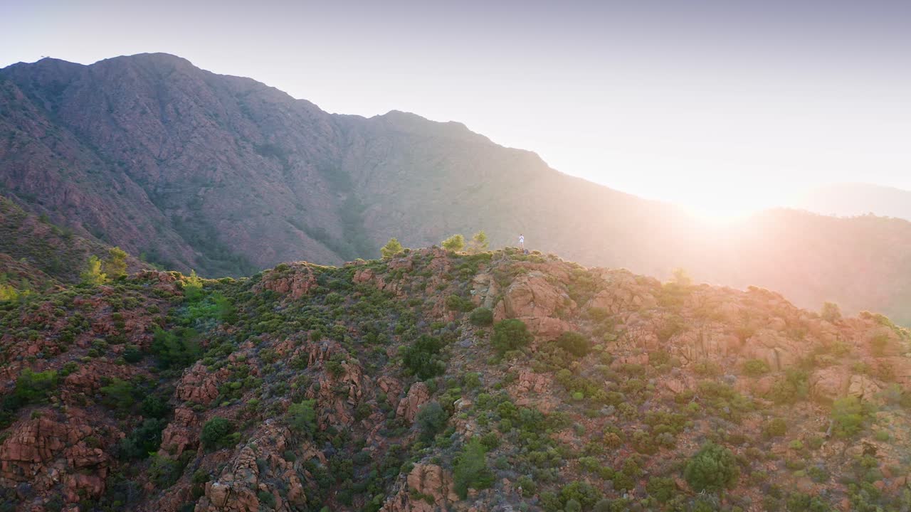 아름다운 해가 뜨는 산꼭대기에 머물고 있는 남자를 둘러싼 경치 좋은 비행