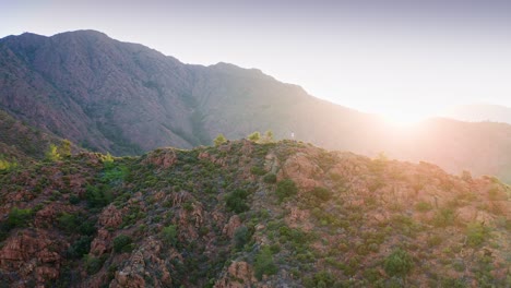 scenic flight around the man staying on the mountain peak at beautiful sunrise