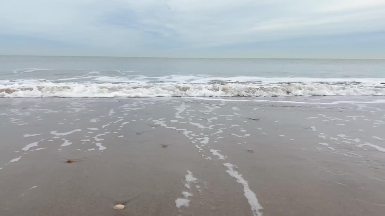 4K Close shot of beach and moving waves from the North Sea, Vlissingen, Netherlands, Zeeland.