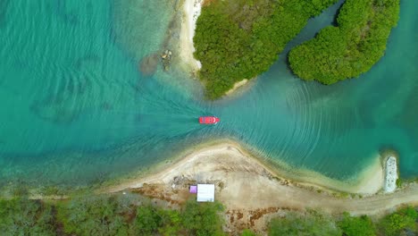 San-juan-harbor-inlet-as-red-boat-slowly-drives-through-channel,-top-down-static