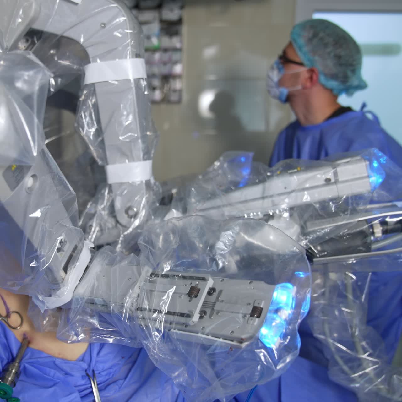 High tech robot operating the human in modern surgery room. Male surgeon in glasses stands near the robot watching the process