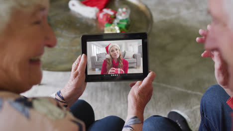 Pareja-Caucásica-Mayor-Usando-Tableta-Para-Videollamada-Navideña-Con-Una-Mujer-Feliz-En-La-Pantalla