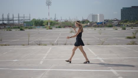 woman walking and talking on a smartphone in a city parking lot