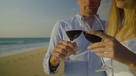Cropped-shot-of-couple-drinking-red-wine-on-beach