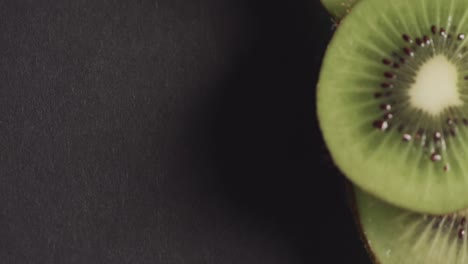 Micro-video-of-close-up-of-kiwi-fruit-slices-with-copy-space-on-black-background