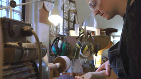 bespoke shoemaker smoothing wooden last for shoe on sander