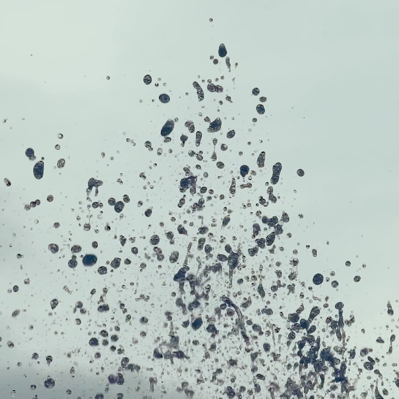 Close-up of fountain water droplets on sunlight. Water splashing. Slow motion