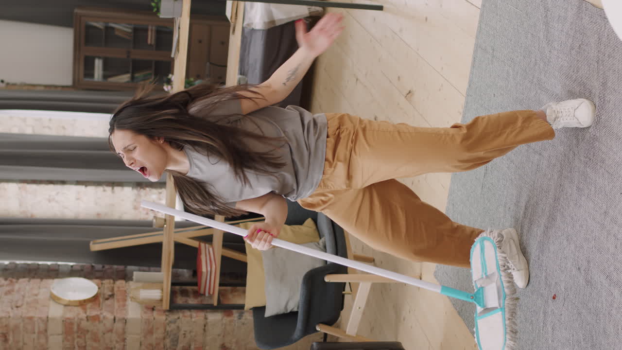 Vertical Shot of Happy Woman with Mop Singing and Dancing
