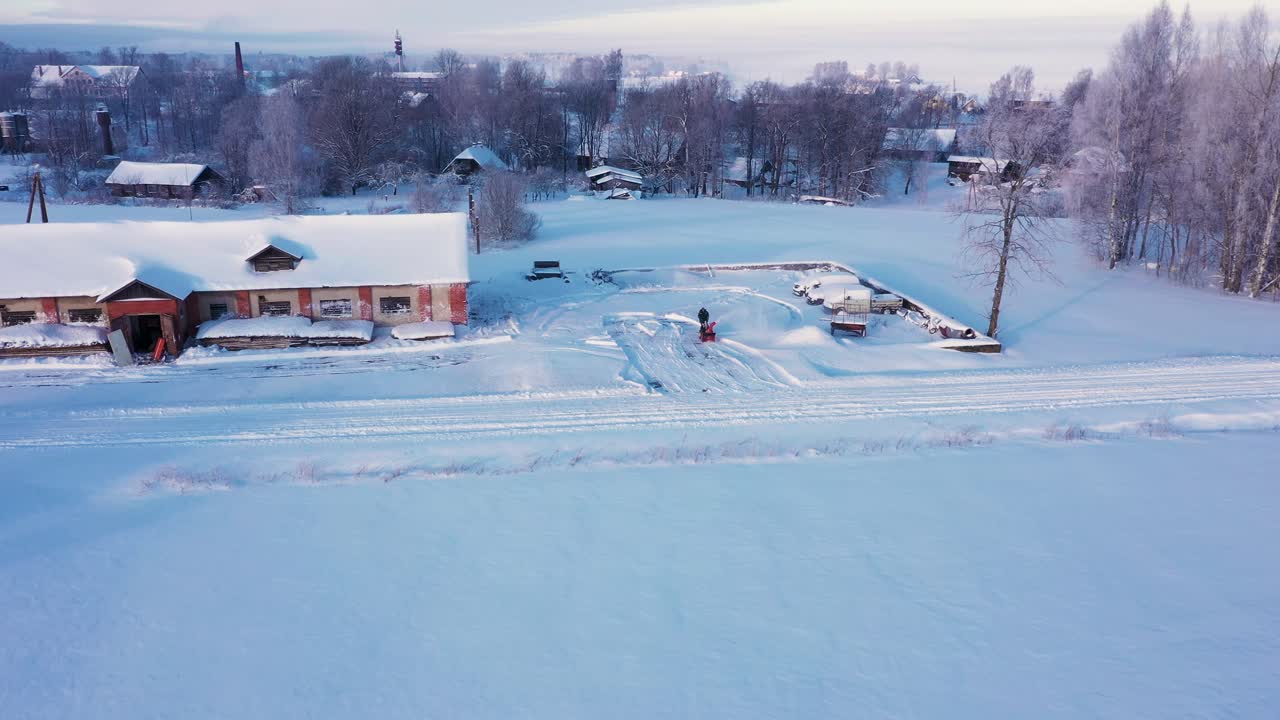 Man som röjer snödriva med en snöslunga på en bostadsuppfart.