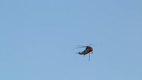 a firefighting helicopter flies high in the sky searching for water for nearby raging national forest wildfire