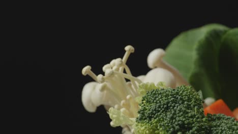close up of a pot of shabu ingredients spinning around on the black background