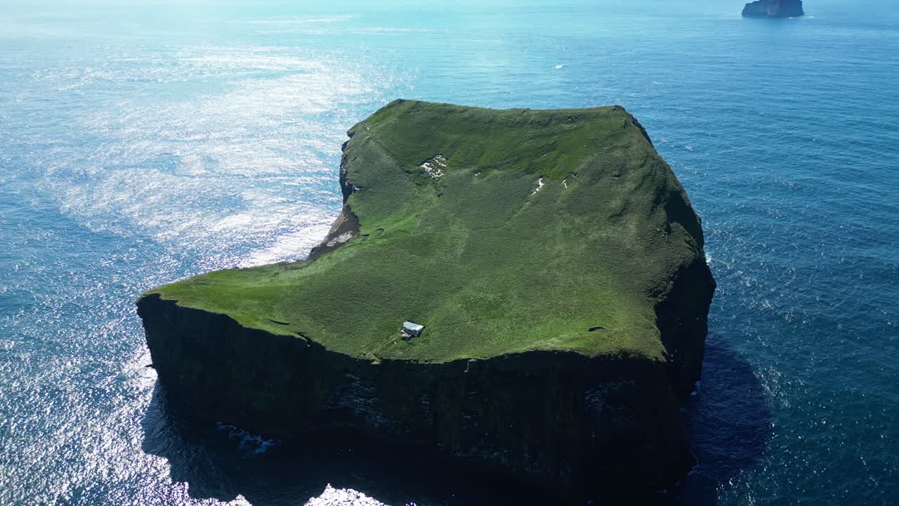 Sunny summer day embracing a lonely hut standing on a remote island with waves washing over the rugged shore and birds flying around
