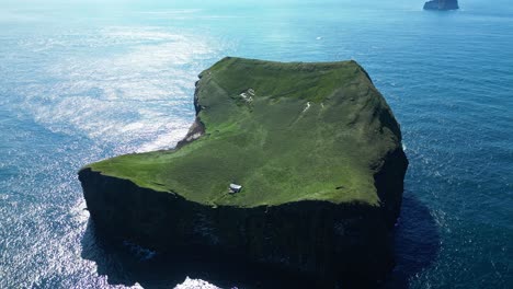 Sunny summer day embracing a lonely hut standing on a remote island with waves washing over the rugged shore and birds flying around
