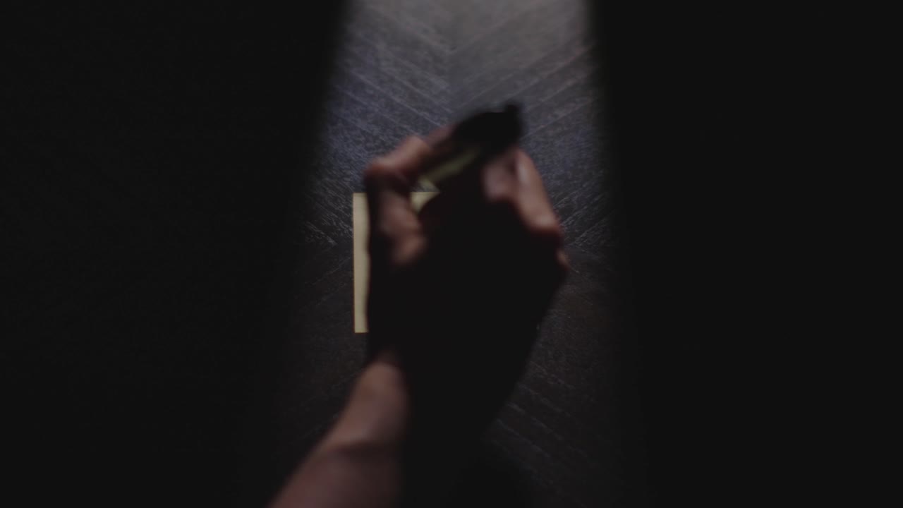 Un primo piano, illuminato in modo drammatico, di una mano che appoggia un Post-it e disegna il numero 8 con un pennarello