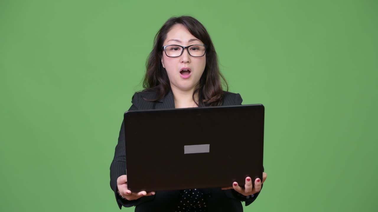 녹색 배경에 노트북을 사용하는 성숙한 아름다운 아시아 사업가