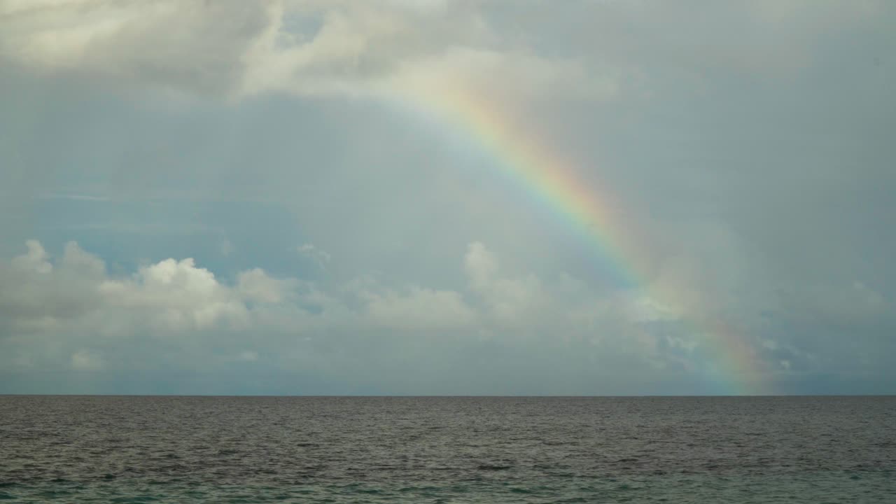 luz solar refractada por las gotas de lluvia creando un arco colorido sobre la superficie del océano.