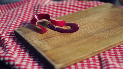 apple peel falling down on wooden board. peel of red apple