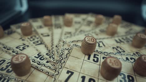 grúa fpv toma giratoria de un juego de lotería de mesa de bingo, tarjetas antiguas con números, fichas de madera, movimiento súper lento 120 fps, luces de estudio