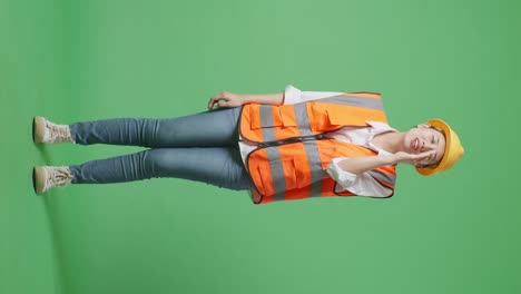 full body of asian female engineer with safety helmet yelling with hand over mouth while standing in the green screen background studio