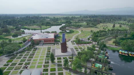 Orbital-footage-above-a-lake-with-view-of-trajineras,-a-highway-and-a-natural-area-in-Xochimilco,-Mexico-City