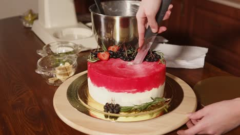 woman cutting a delicious layered cake decorated with berries