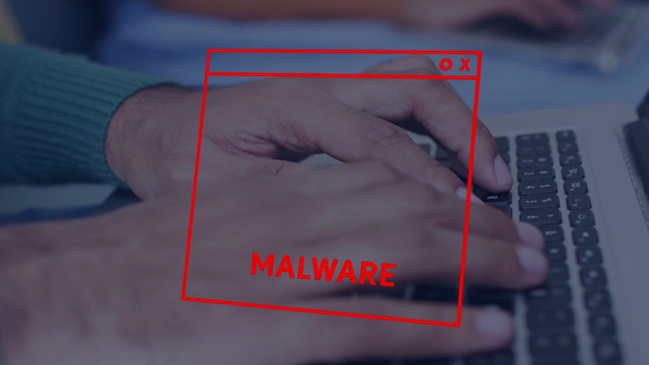 Mand taster på bærbar computer, mens en rød malware-advarsel vises og glitcher over tasterne, og han forsøger at fortsætte arbejdet.